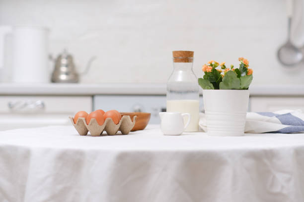 istock Easter celebration concept. Easter eggs, bottle of milk, flowers in white pot on white table in light kitchen. 2073856685