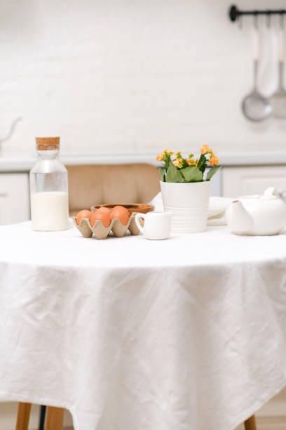 istock Easter celebration concept. Easter eggs, bottle of milk, flowers in white pot on white table in light kitchen. 2073860498