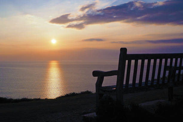 istock Wooden bench overlooking peaceful bright orange sunset across ocean 2073879421