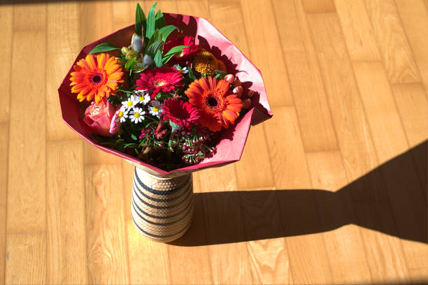 A bouquet of colorful flowers in a vase placed in a sunny highlighted area.The perfect gift for a woman, be it your girlfriend, partner or mother  especially on international woman's day. A good idea to décor the house too.