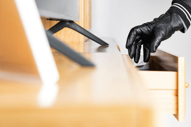 Hand of an unknown thief stealing in a drawer