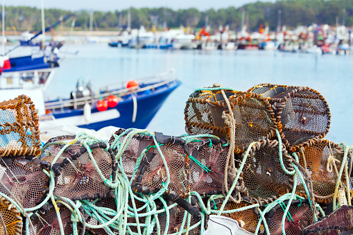 Heap of fishing net baskets on harbor dock, fishing boats .  O Grove, Pontevedra province, Rías Baixas,Galicia, Spain.