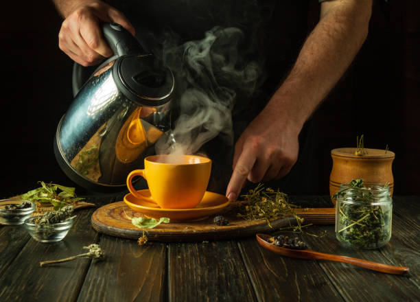 istock A man brews tea with medicinal herbs on the kitchen table. Traditional medicine concept at home. Adding boiling water to a mug 2073907067