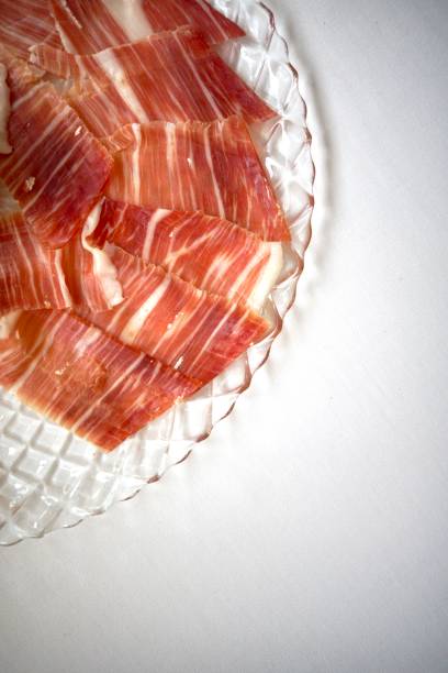 Thinly sliced Iberian ham on a crystal clear plate.