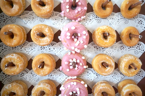 Overhead view of assorted donuts displayed on a lace-lined shelf.