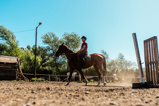 Teenager boy horseback riding on a stable