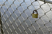 Valentine heart padlock attached to wire mesh fence. Love padlocks hanging on a bridge