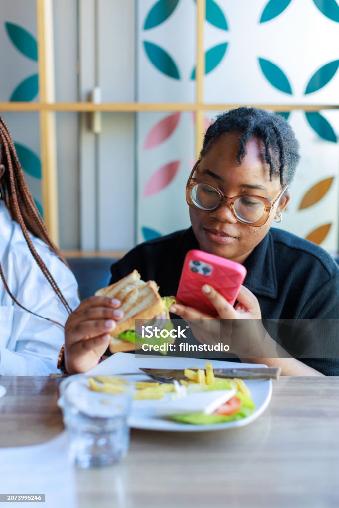 Student Eating Visual Female Student Eating At A Café And Browsing Her Phone Stock Photo ...