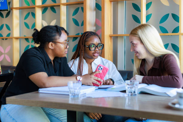 istock Young Female Students Talking And Using Mobile Phone At Cafe 2074032042
