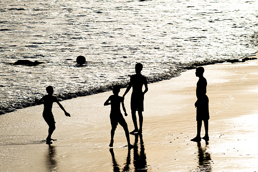 Silhouette of three young man walking on the beach in the early morning