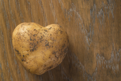 fresh raw heart shape potato on wood background with copy space, organic food
