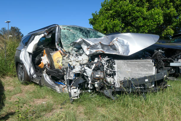 Firefighters rescuing an injured man in mangled car.\