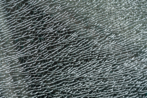 Window glass shattered by a shell fragment. Broken window glass close-up.