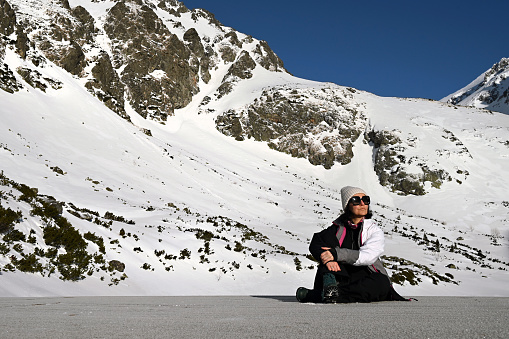 Woman sitting in front of mountains covered with snow near Sliezsky Dom hotel