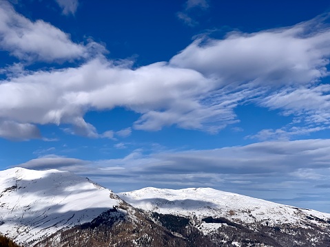 beautiful clouds in a blue sky over the snow-capped Piedmont Alps in the Varaita valley