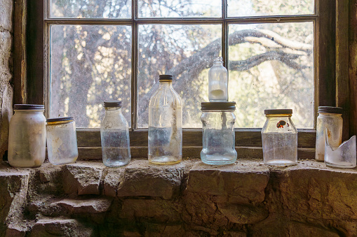 Old antique glass bottles sitting in a row on a window sill of Eagle Cliff Mine cabin at Joshua Tree National Park, California