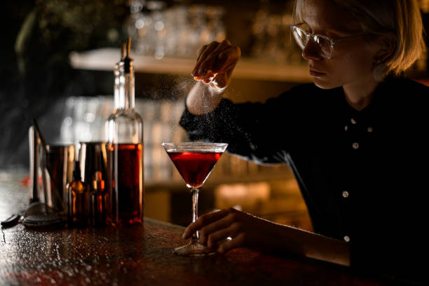 istock Woman bartender splashing orange peel into ready red cocktail 2074225042