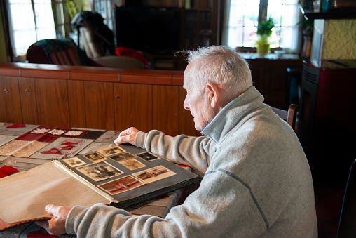 Memories. Retirement. An elderly man scrolls photos on a family album.