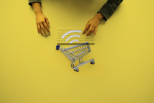 Woman using computer keyboard and mouse with shopping cart