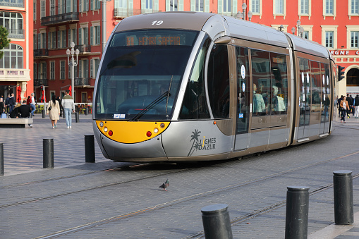 Nice, France - April 22, 2023: Modern tram on its way through the city centre. You can see people walking in Place Massena