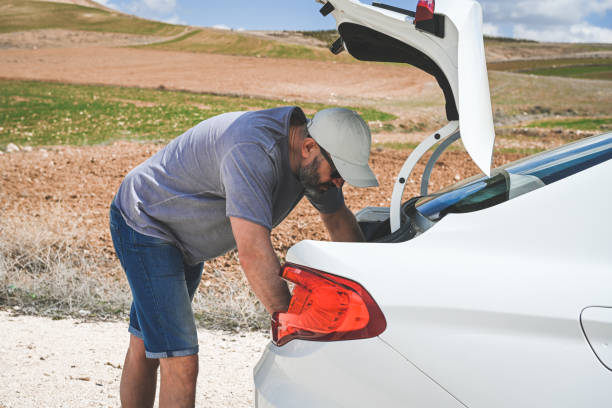 man stands by a broken car - stranded travel people traveling disappointment - fotografias e filmes do acervo