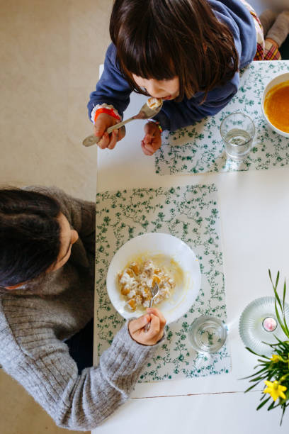 istock upper view of two siblings eating lunch at home at white table 2074300424