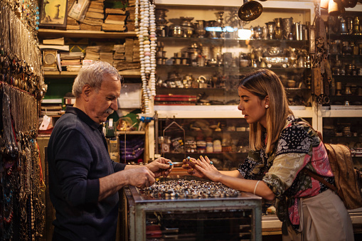 Providing excellent service, the jeweler owner helps a customer find the perfect piece