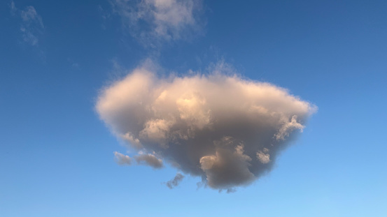 Lonely gray cumulus cloud at sunset with blue sky