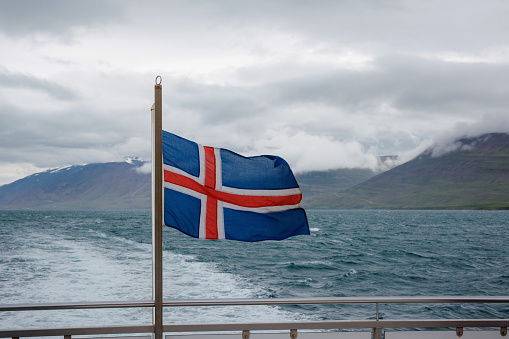 National flag of Iceland waving in the wind on the ship leaving the harbor, close up shot. Adventure, travel, and holiday concept.