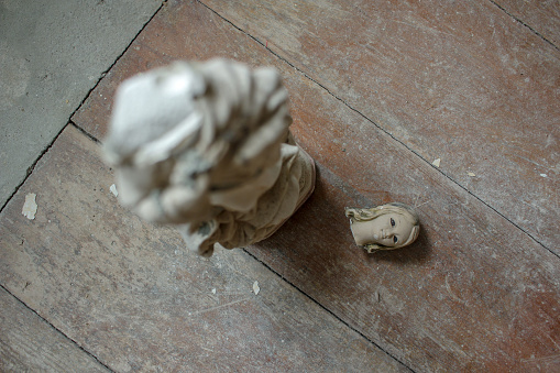 a small statue of a virgin with its head broken on the ground