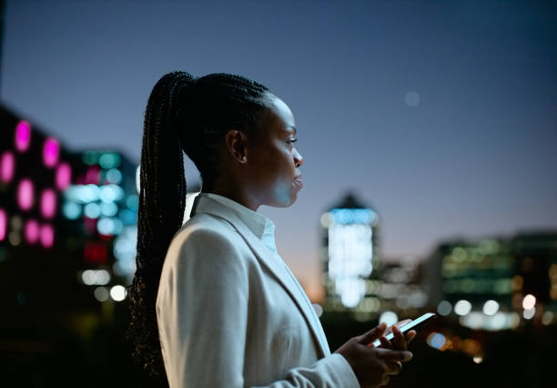 Business, woman and smartphone at night with thinking in city for communication, email or text message on rooftop. Employee, black person and thoughtful with phone for internet scroll or social media negocios, mujer y teléfono inteligente por la noche con pensando en la ciudad para la comunicación, el correo electrónico o el mensaje de texto en la azotea. empleado, persona negra y reflexivo con teléfono para desplazamiento de internet o redes socia