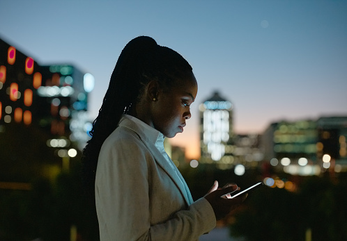 Business, woman and reading smartphone at night in city for communication, email or text message on rooftop. Entrepreneur, black person and phone for internet scroll, social media and chat with bokeh