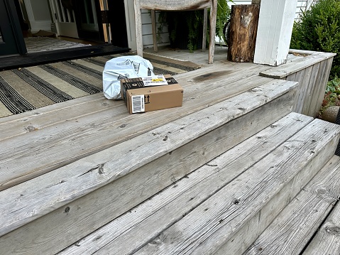 port perry, canada - august 16 2023: a brown box delivery package of amazon has been left on someones porch