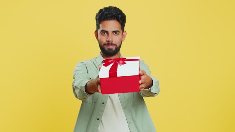 Smiling man presenting birthday gift present box stretches out hands, promotion discount sale