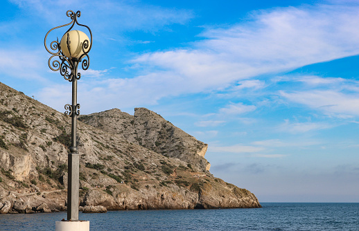 Picturesque coastline, a lantern on the embankment against the backdrop of the blue sky and sea. Travel, vacation, trip concept