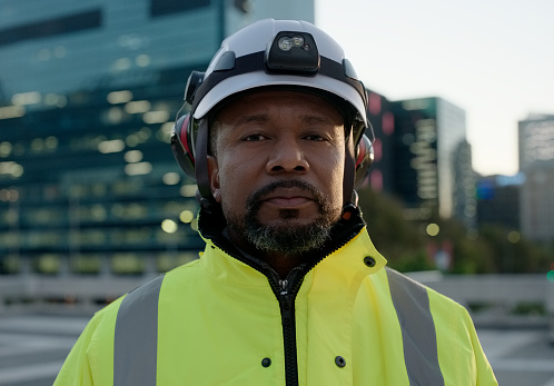 Man, construction worker and portrait in city with office building for urban project planning, development or confidence. Male person, face and infrastructure for contractor, engineer or confident