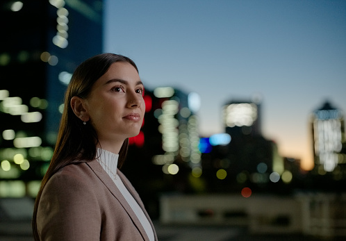 Business, night and woman in city thinking with career opportunity, vision and planning. Dark sky, buildings and face of businesswoman with insight, inspiration and professional outside urban street.