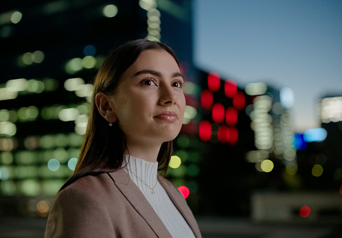 Business woman, thinking and city at night with smile for career opportunity, planning and job goals in urban bokeh. Professional person, accountant or worker for vision, inspiration or ideas outdoor