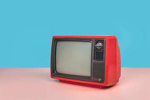 Retro red old television with blank screen on pink floor with copy space, colorful vintage analog TV with mint blue wall background.