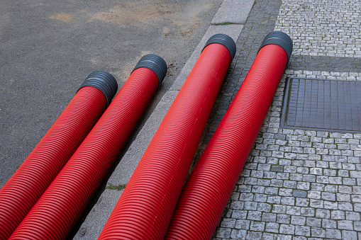 red corrugated pipe are buried underground on the street. underground electric cable infrastructure installation. Construction site with A lot of communication Cables