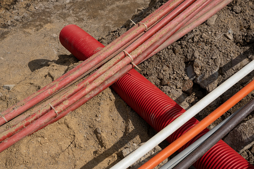 A large number of electric and high-speed Internet Network cables in corrugated pipe are buried underground in cable infrastructure installation. Construction site