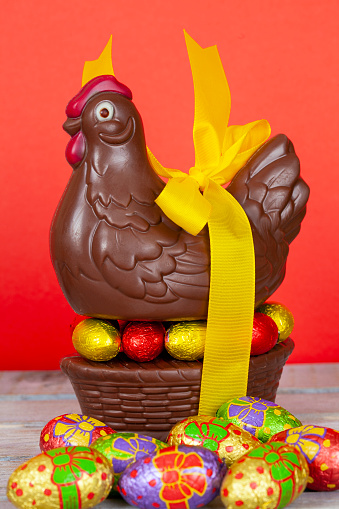 Easter chocolate chicken and eggs over a white rustic wooden table