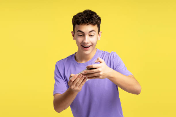 istock Excited, smiling, attractive teenager holding mobile phone, using mobile app, playing game 2074493957