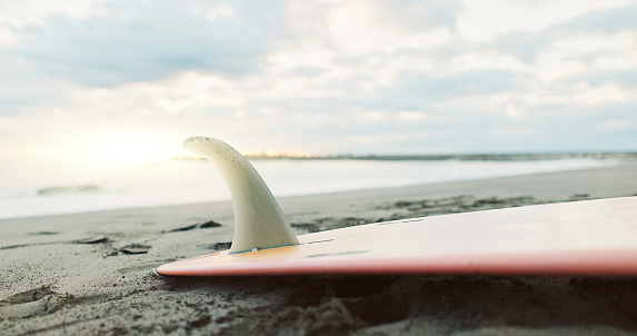 Beach, sand and surfboard at ocean water in the background on summer vacation, travel or holiday in Japan. Sea, surf and sports in nature outdoor for adventure, action or recreation on a landscape