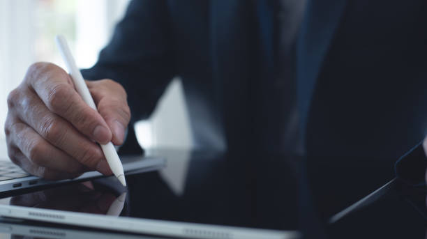 istock Businessman, manager working, using stylus pen signing e-document on digital tablet with laptop computer on table at modern office, e-signing, electronic signature, work planning, digital document concept 2074551059