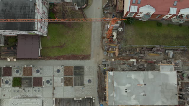 Aerial top down shot crane in residential area of polish city at cloudy day. Roofing and grass with parking area.