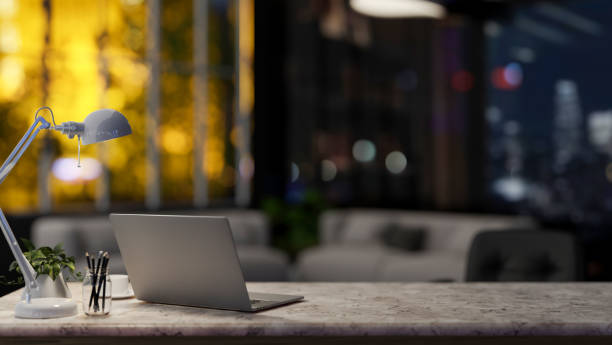 istock A laptop computer on a marble table in a modern spacious living room or private office at night. 2074664162