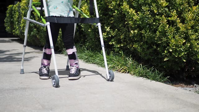 child with walking frame and knee orthosis outdoor