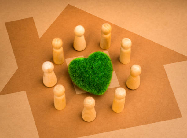 istock Green common area, revitalizing volunteer group, cooperation community eco sustainability, environment responsibility concepts. wooden people figures surround green heart on big home shape background. 2074765762