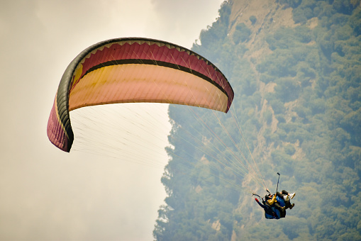 Young man paragliding with an instructor over beautiful mountain of Himachal Pradesh, Bir- Billing India.